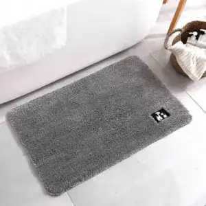 Grijze antislip badmat voor de douche, met zwart logo op lichte tegelvloer.