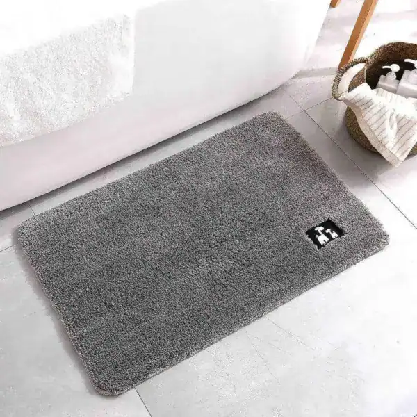 Grijze antislip badmat voor de douche, met zwart logo op lichte tegelvloer.