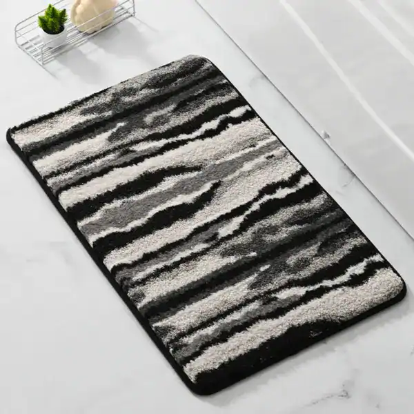 Zwart-wit gestreepte badkamermat met antislip rand, voor bad of douche.