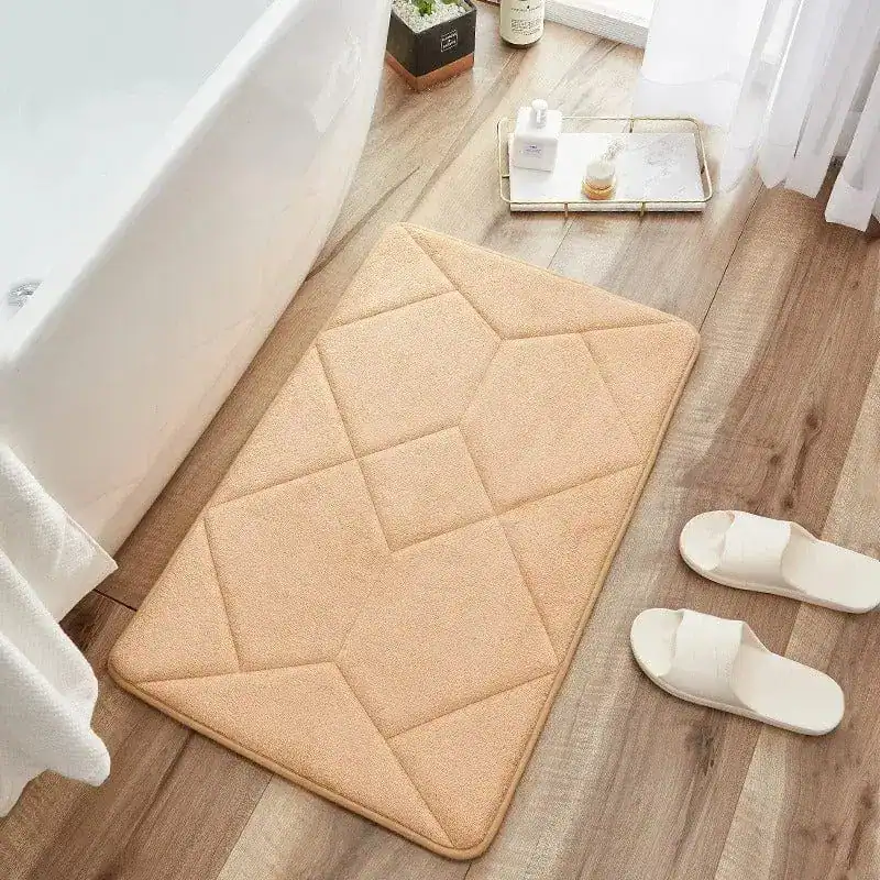 Beige badmat met antislip structuur, geplaatst voor een bad in een badkamer.