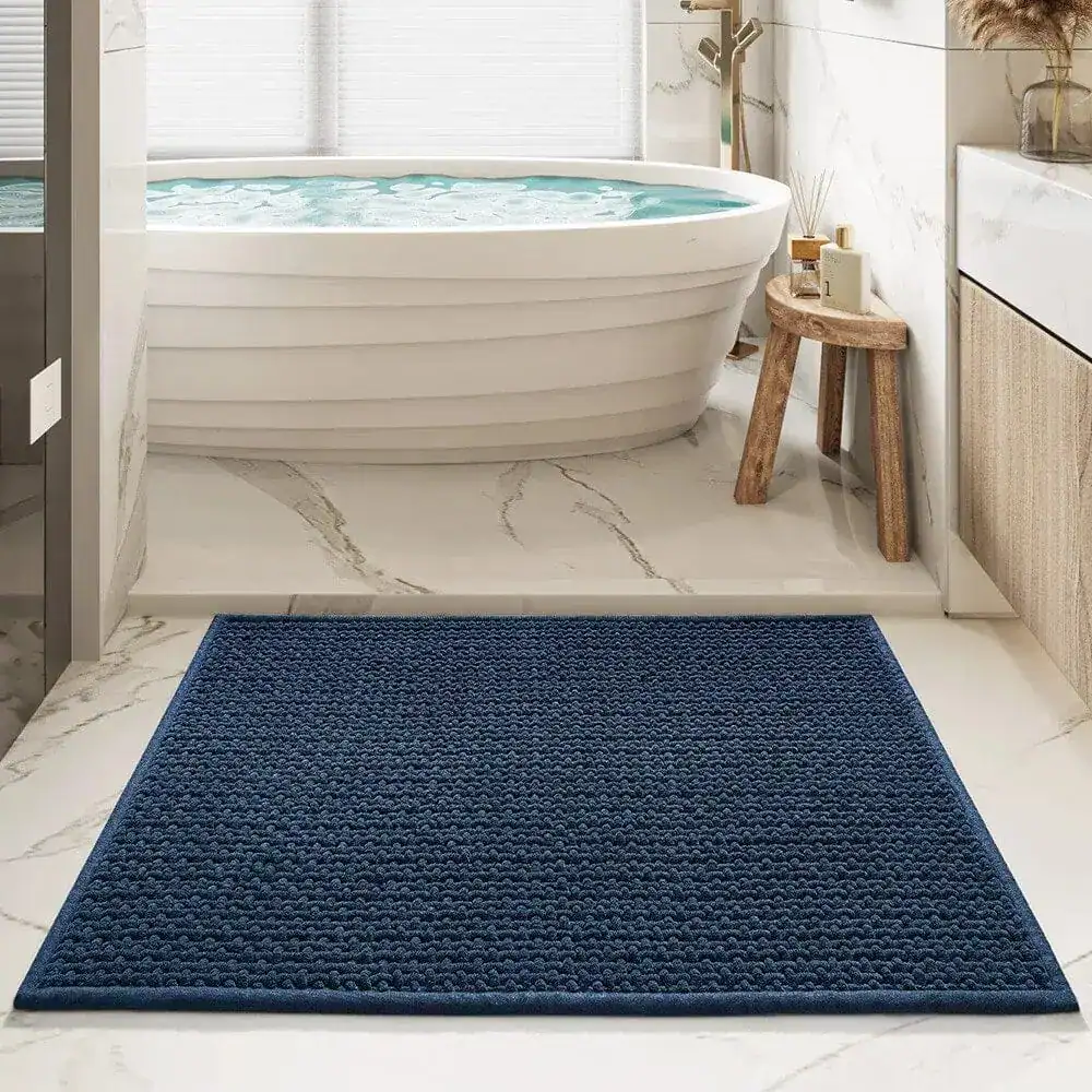 Donkerblauwe badmat voor de badkuip met antislip textuur in een moderne badkamer.