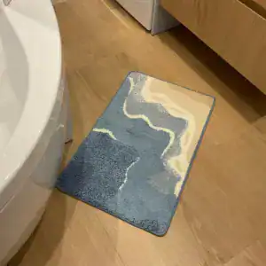 Blauwe badmat met golvend motief naast een vrijstaand bad