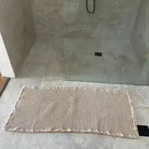 Beige wafelbadmat met franjes in een inloopdouche