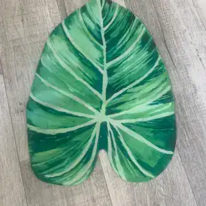 Badmat in de vorm van een groen blad op een houten vloer