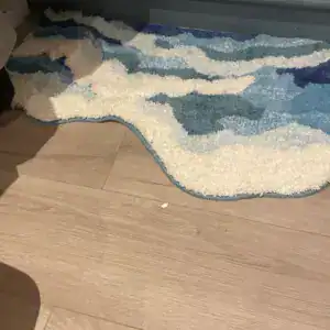 Blauw-witte getufte badmat met wolkenmotief op parket