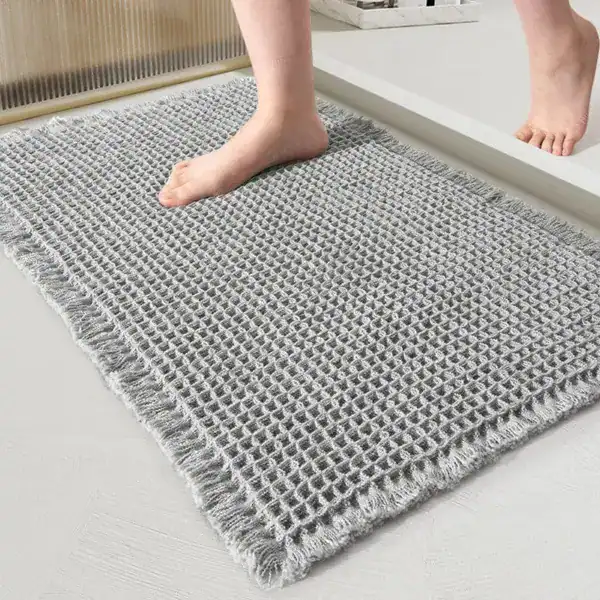 Grijze badmat met jute look en franje, antislip voor badkamer.