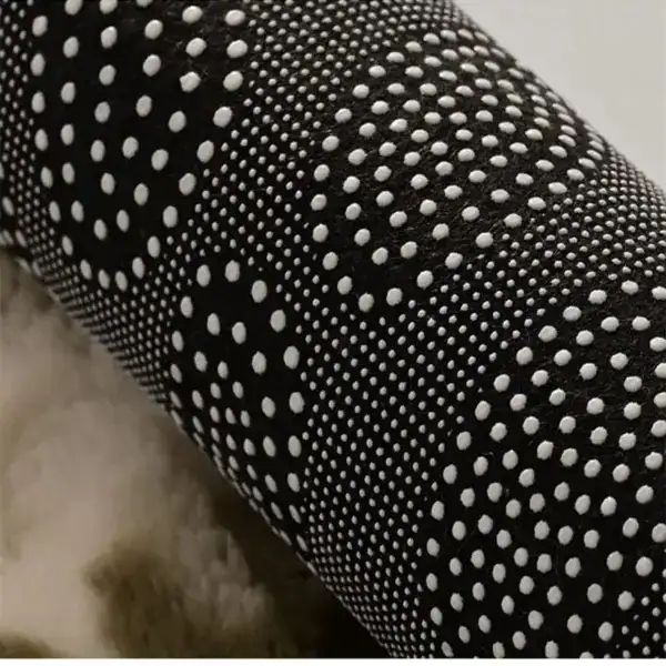 Zwarte badmat met witte antislip stippen, close-up van de textuur.