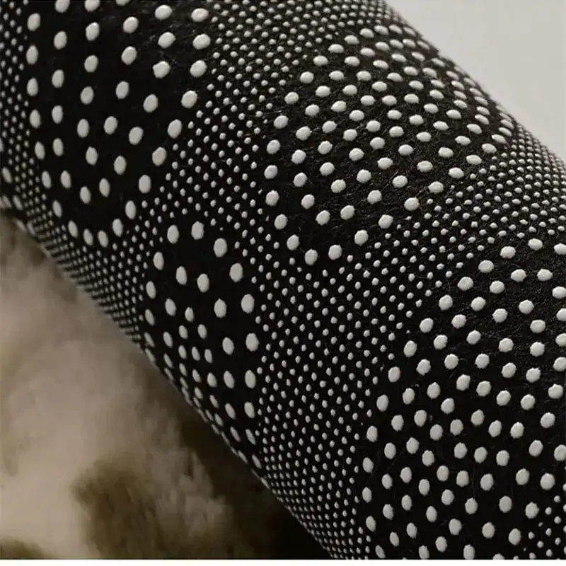 Zwarte badmat met witte antislip stippen, close-up van de textuur.