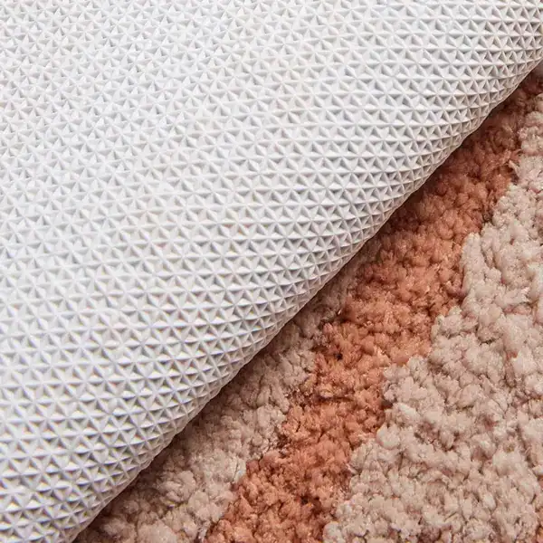 Ronde witte badmat met antislip textuur, gelegd op kleurrijke vloerbedekking.