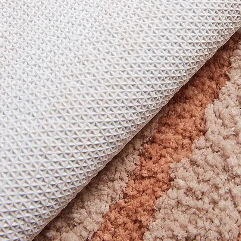 Ronde witte badmat met antislip textuur, gelegd op kleurrijke vloerbedekking.