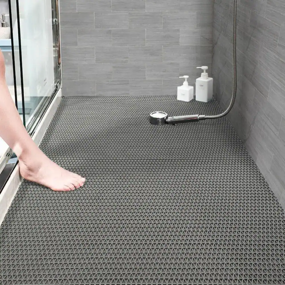 Donkergrijze antislip badkamermat met driehoekig patroon in de douche.