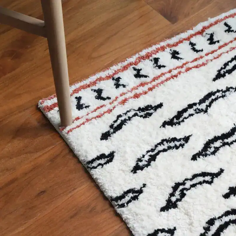 Badmat zwart beige met geometrisch patroon op houten vloer.