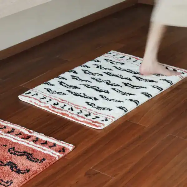 Zwarte en beige badmat met patroon op houten vloer, antislip badkamermat.
