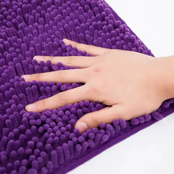 Paarse chenille badmat met antislip structuur, hand op de mat voor textuur.