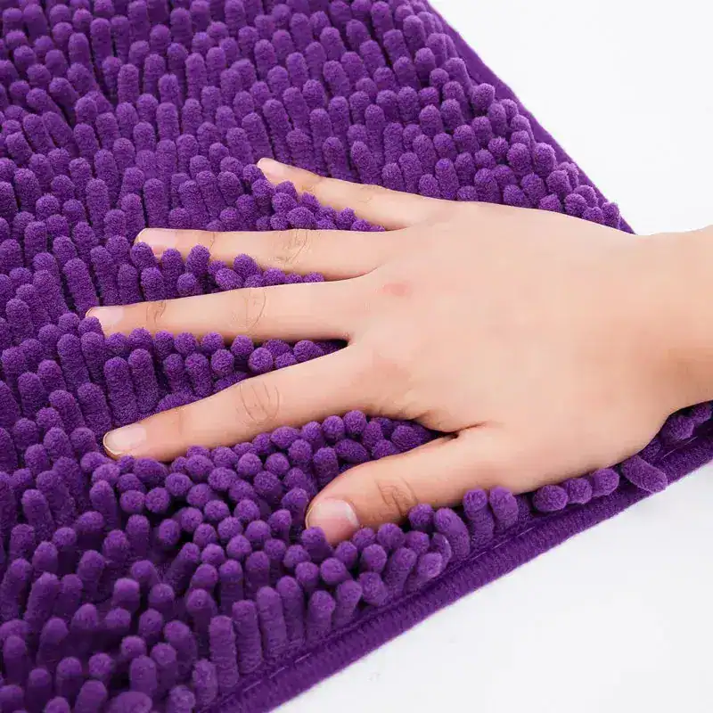 Paarse chenille badmat met antislip structuur, hand op de mat voor textuur.
