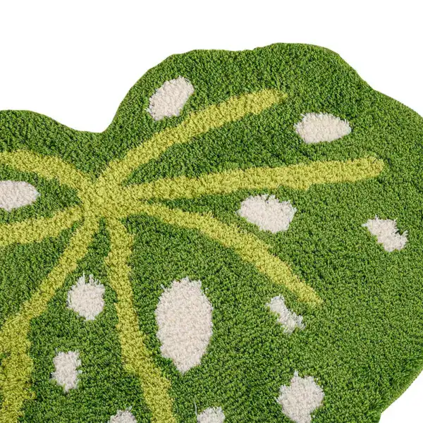 Groene badkamermat in bladvorm met witte stippen en gele aderen.