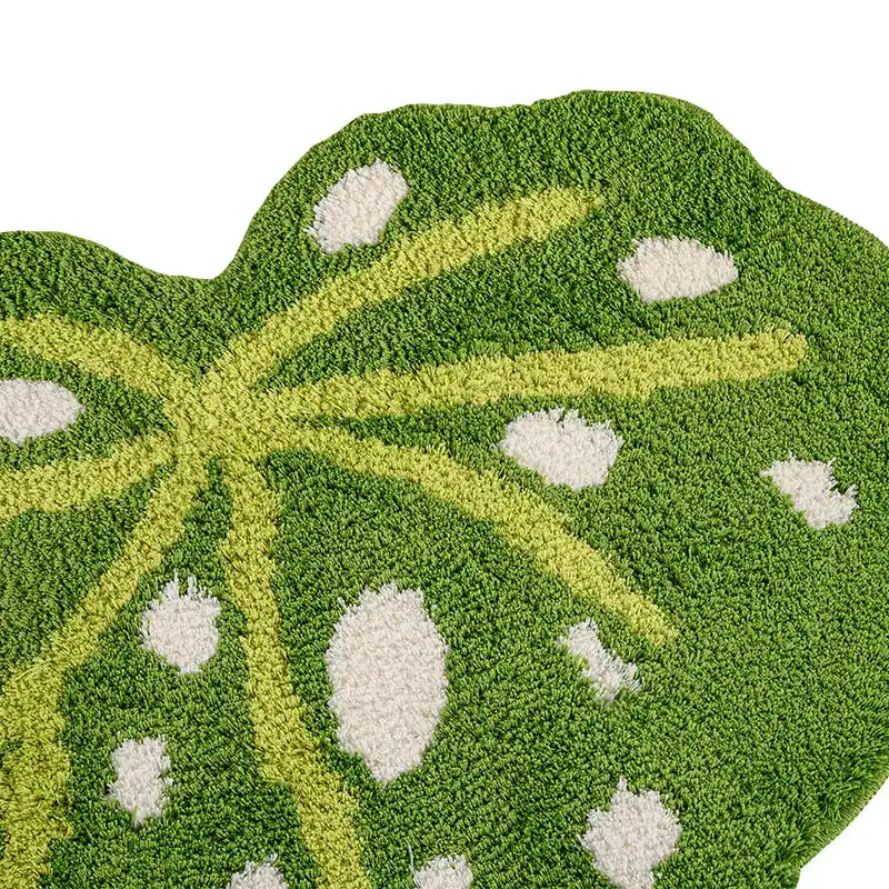 Groene badkamermat in bladvorm met witte stippen en gele aderen.