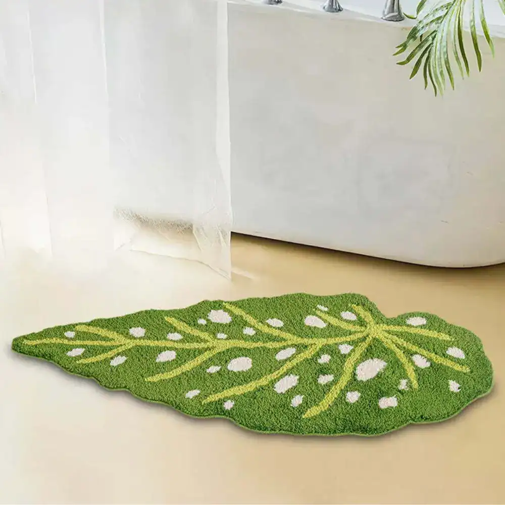Groene bladvormige badmat met witte stippen en geel nervenpatroon.