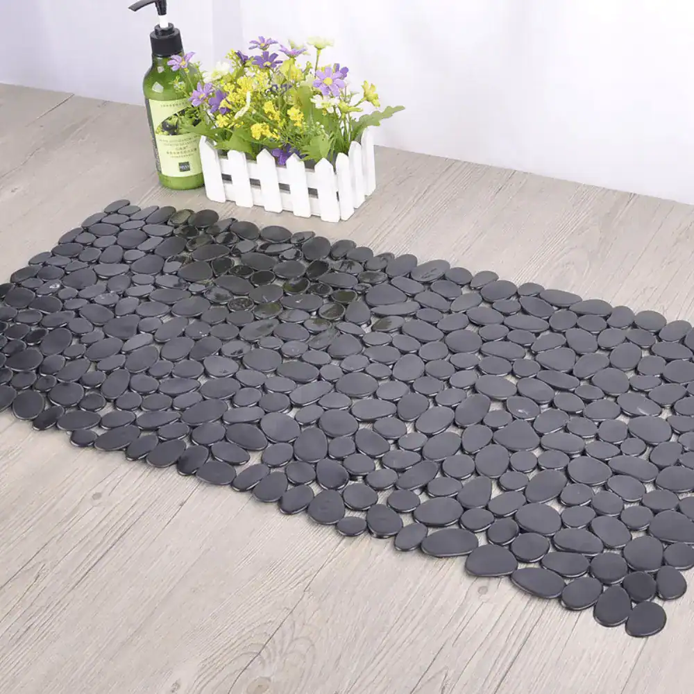 Zwarte rubber badmat met antislip oppervlak, geplaatst op houten vloer in badkamer.