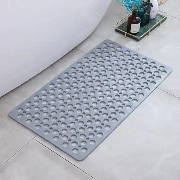 Grijze sneldrogende douchemat met gaten voor antislip effect in badkamer.