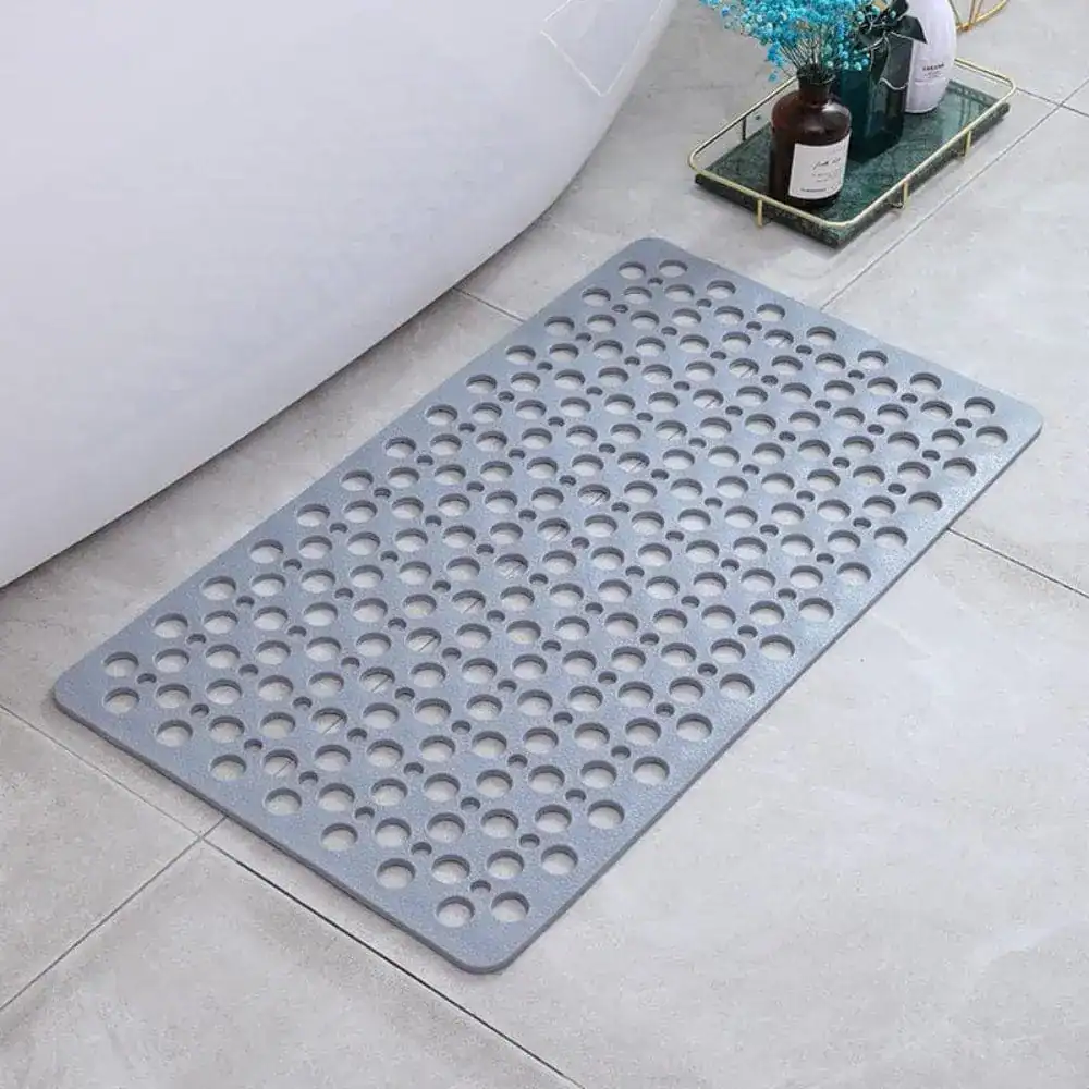 Grijze sneldrogende douchemat met gaten voor antislip effect in badkamer.