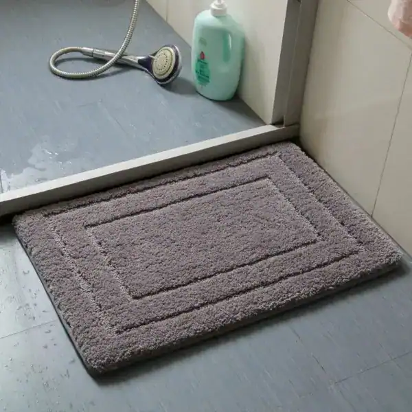 Grijze badmat met randdetail in de badkamer, antislip en super absorberend.