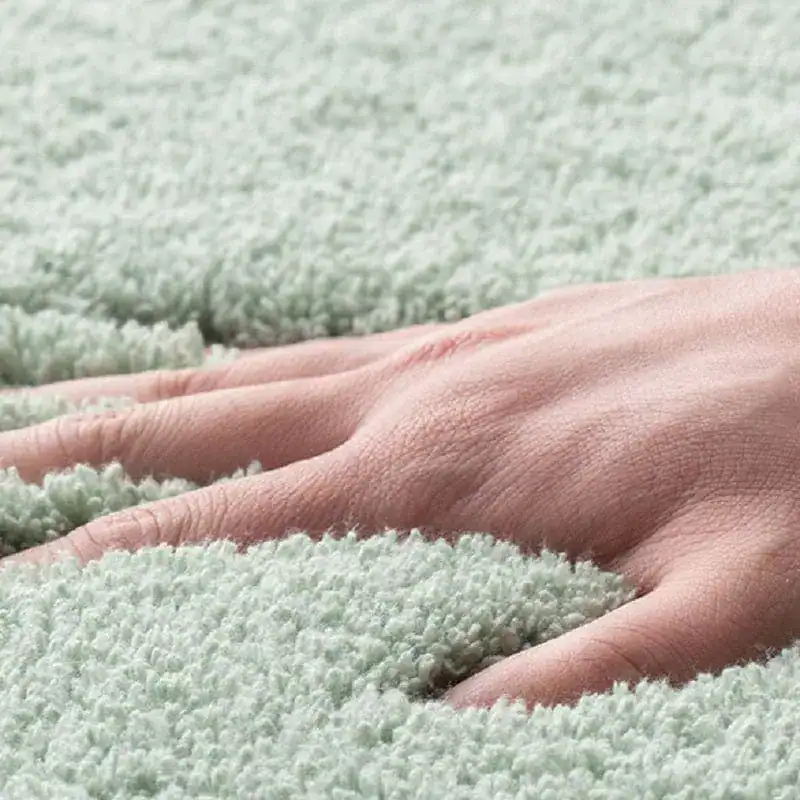 Zachte badkamermat in mintgroen, met hand op de textuur.