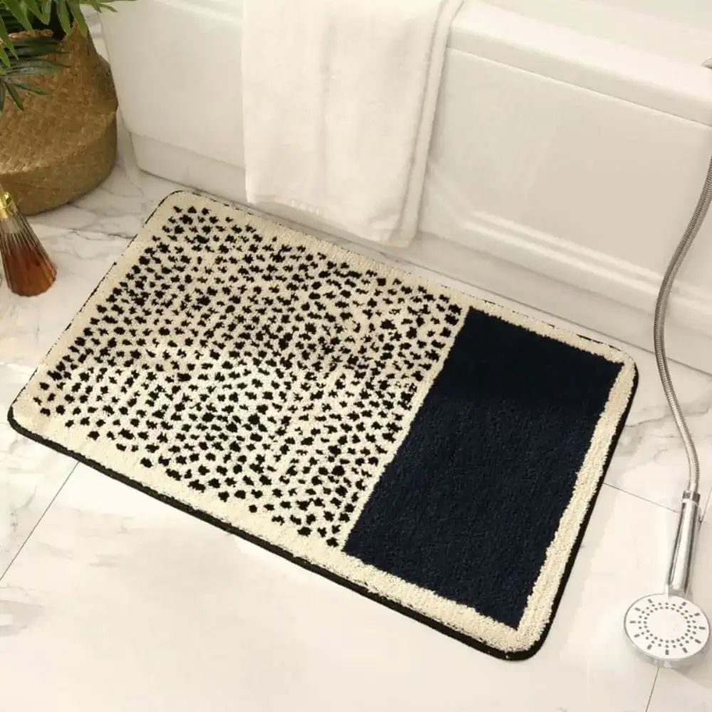 Zwarte en witte badmat met stippenpatroon en antislip rand.